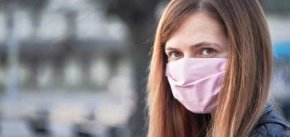 Young woman with hand made face nose mouth mask portrait, blurred empty city square behind her. Can be used during coronavirus covid-19 outbreak prevention